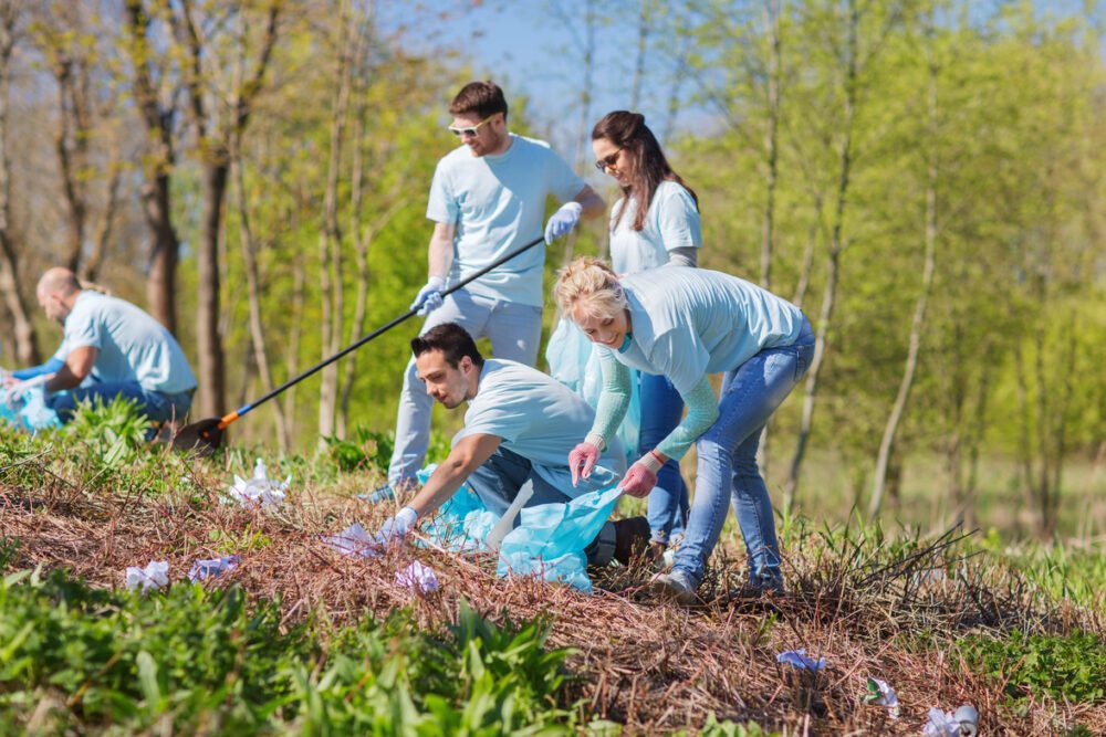 volunteers with garbage bags cleaning park area